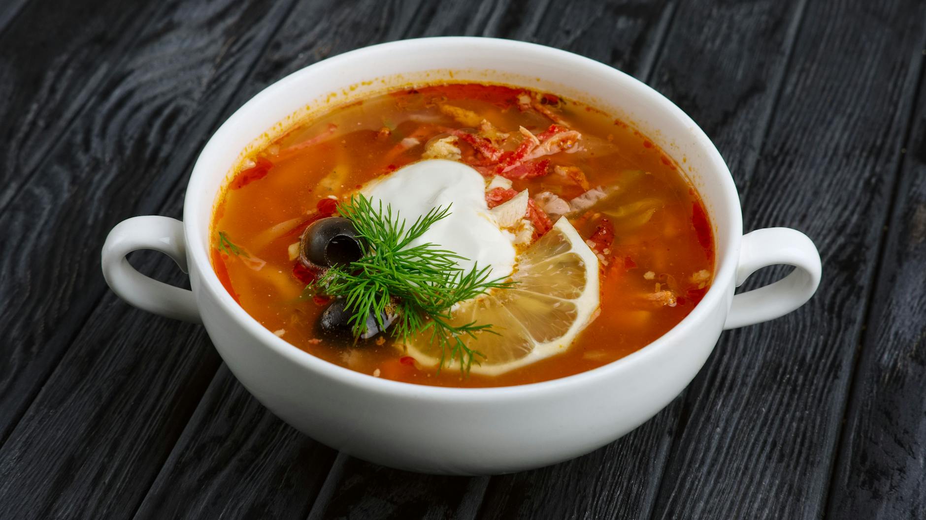 Die Soljanka kann man nach Belieben mit saurer Sahne verfeinern.