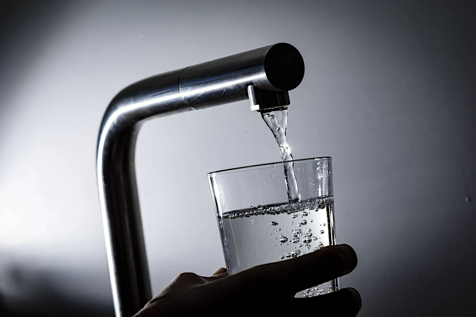 Wasser fließt aus einem Wasserhahn in ein Glas.&nbsp;
