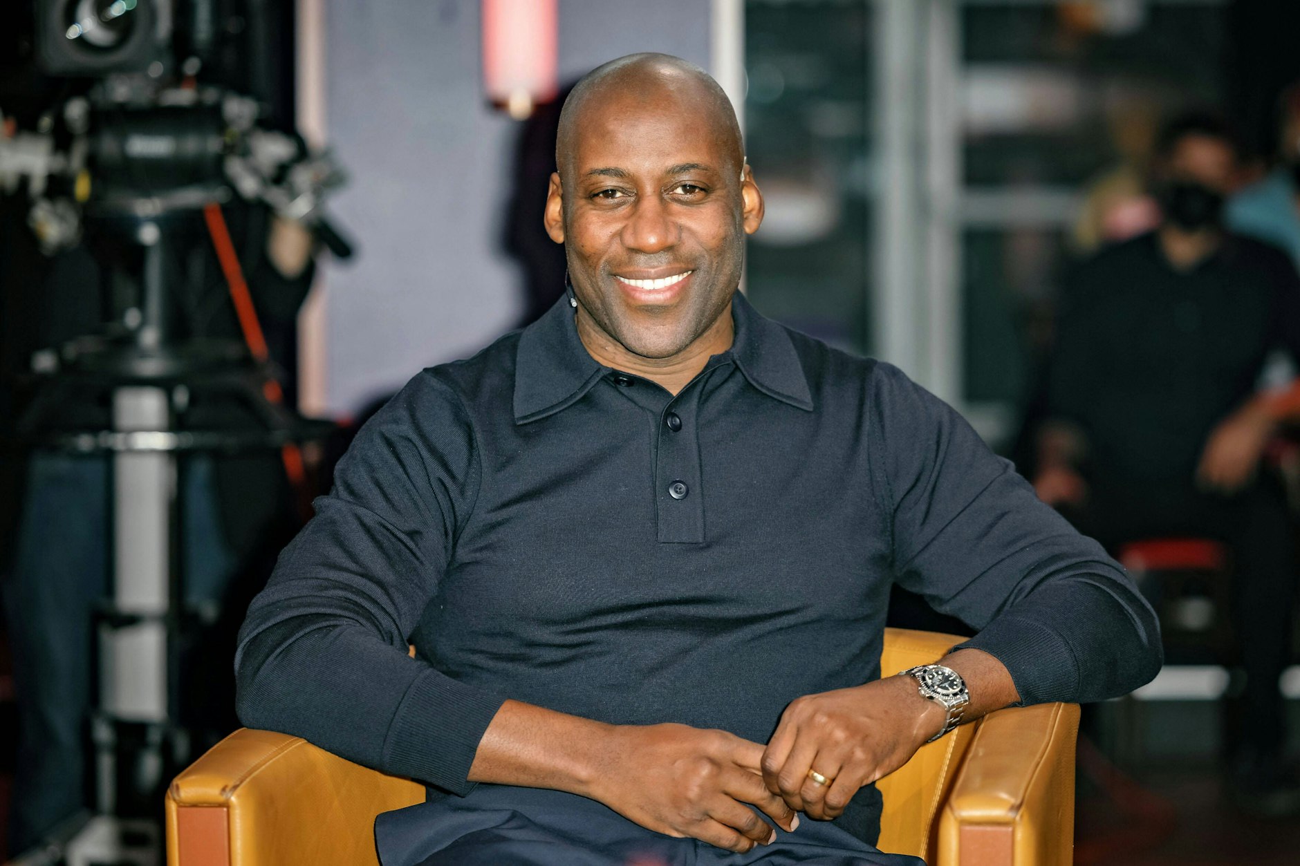 Einer seiner besten Looks: Joe Chialo in einem gut sitzenden, dunkelblauen Polopullover. Am linken Handgelenk trägt er die Rolex Submariner, ein 1953 als Taucheruhr eingeführter Uhrenklassiker.