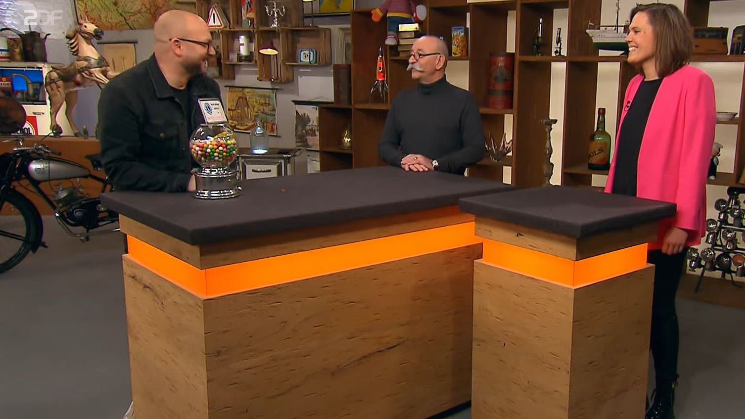 Verkäuferin Julia präsentiert alten Automaten bei „Bares für Rares“-Moderator Horst Lichter und seinem Experten Sven Deutschmanek (l.).