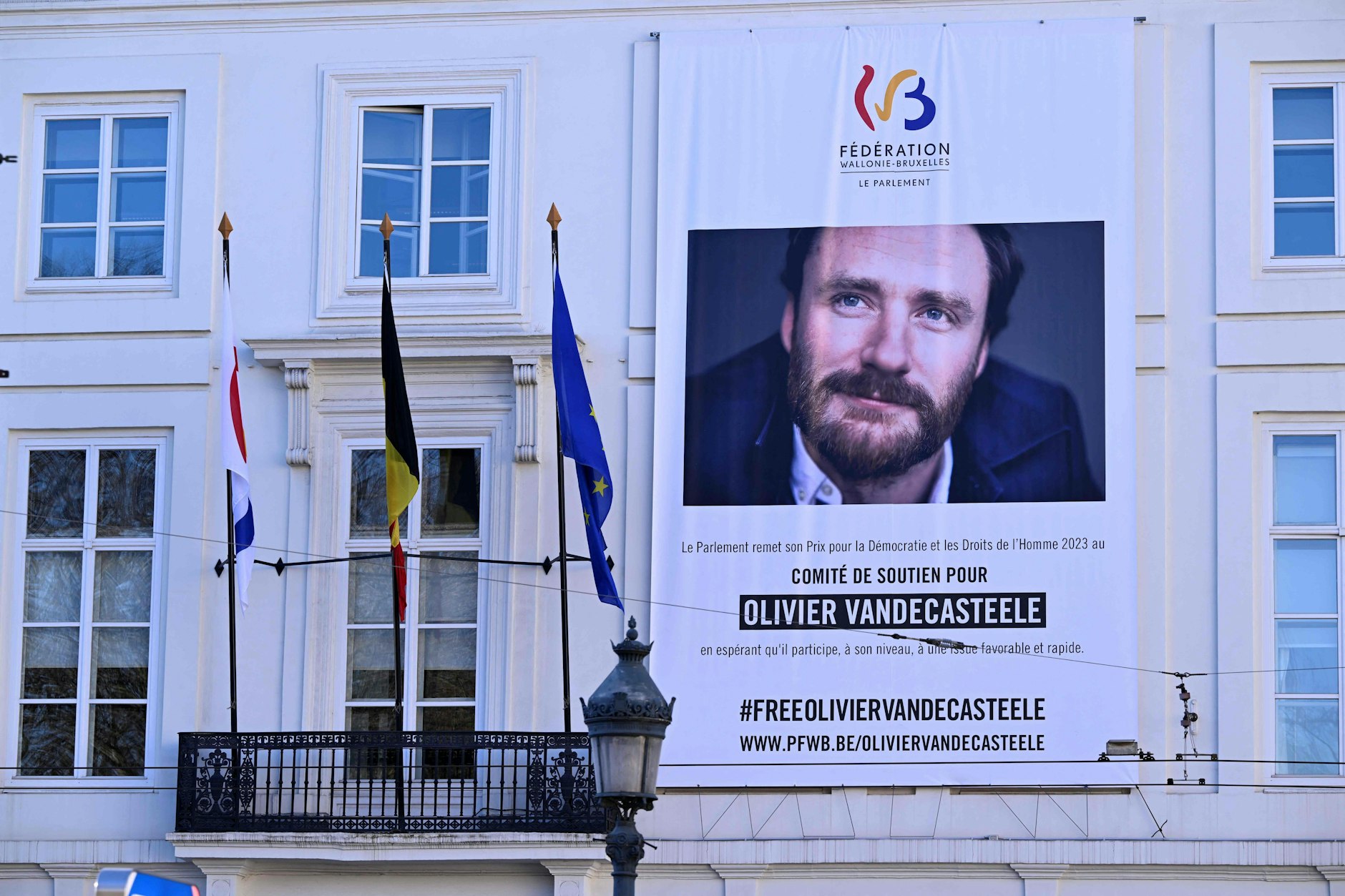 An einem Parlamentsgebäude in Brüssel hing dieses Riesenplakat mit dem Porträt Olivier Vandecasteeles und der Forderung nach seiner Freilassung.