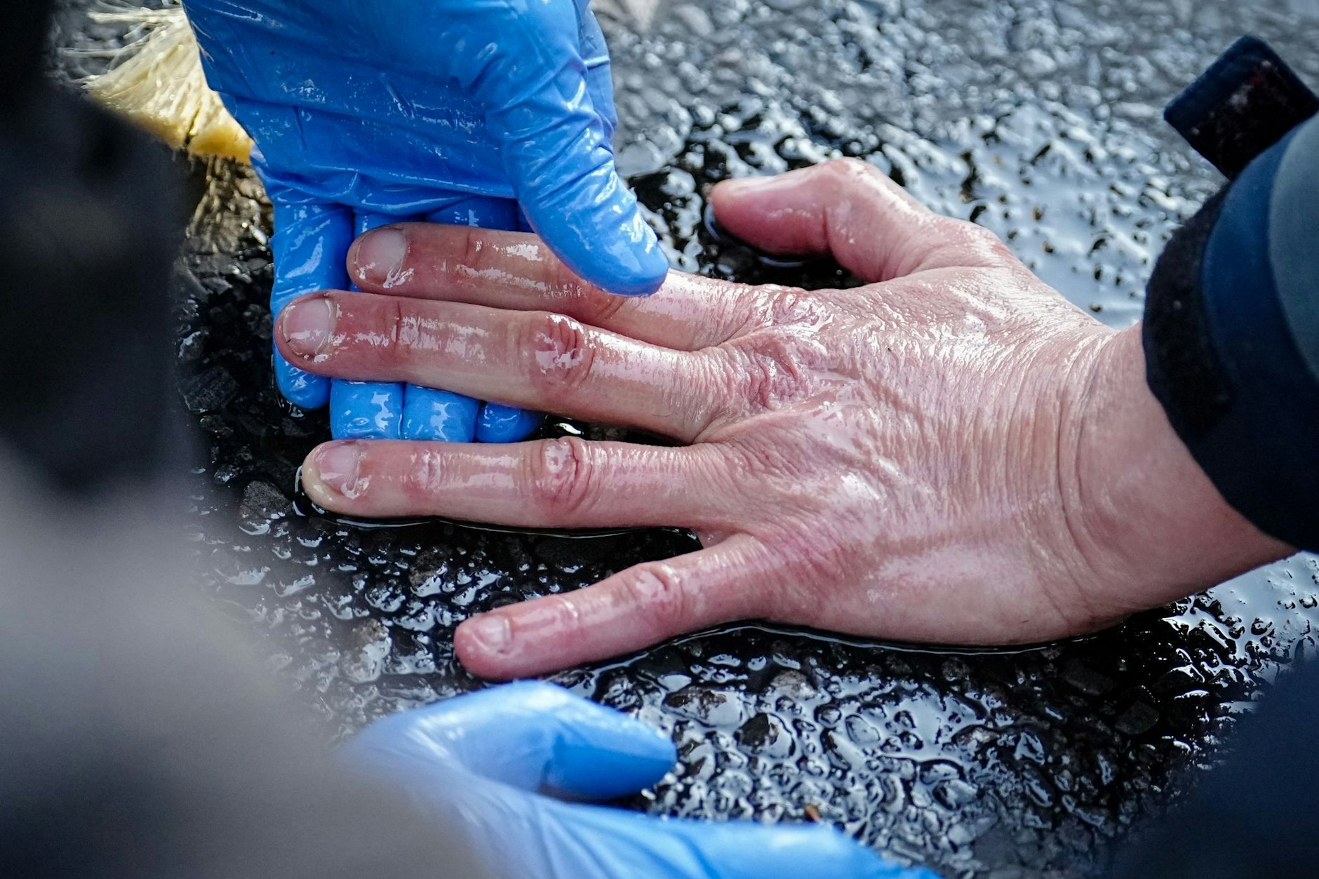 Ein Polizeibeamter löst die Hand eines Klimaaktivisten von der Straße. Foto: Kay Nietfeld/dpa