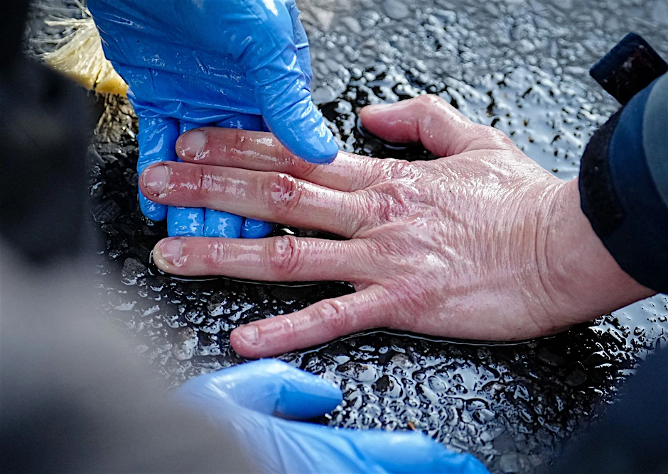 Ein Polizeibeamter löst die Hand eines Klimaaktivisten von der Straße. Foto: Kay Nietfeld/dpa
