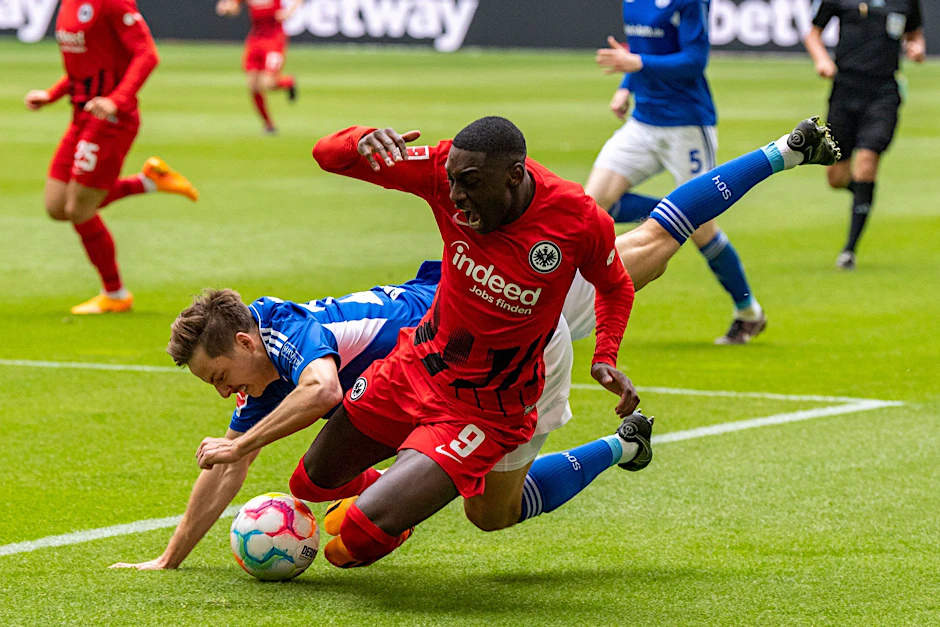 Schalkes Cedric Brunner (l) und Frankfurts Randal Kolo Muani gehen im Zweikampf zu Boden.  