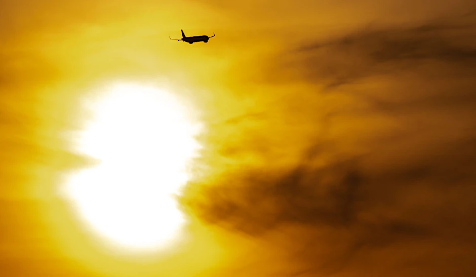 Eine Passagiermaschine startet vor der aufgehenden Sonne in den Tag.  
