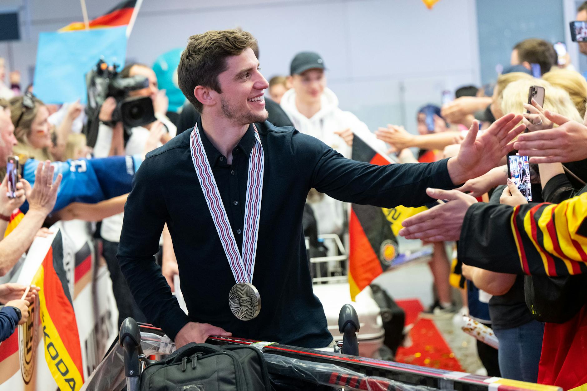 Neu-Eisbär Freddy Tiffels steigt schon in München mit Silber um den Hals aus dem Flieger, wird auf dem Flughafen von den Fans gefeiert.