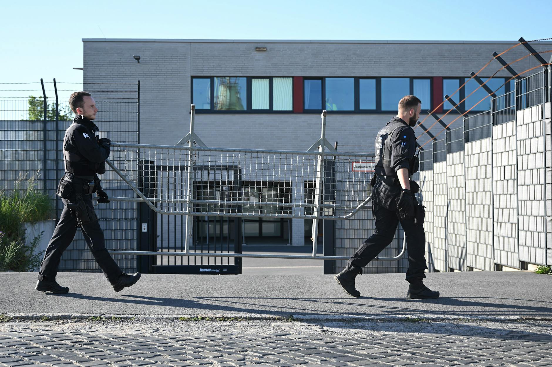Polizisten tragen vor Beginn der Urteilsverkündung gegen Lina E. und drei Männer vor dem Oberlandesgericht (OLG) Dresden ein Absperrgitter entlang. Die mutmaßliche Linksextremistin wurde am Mittwoch verurteilt.
