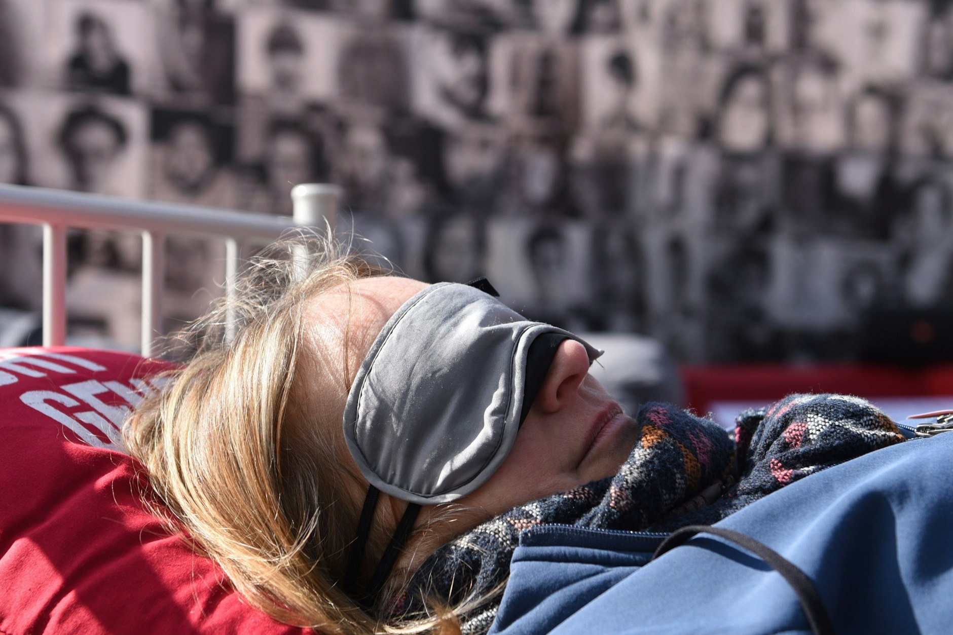 Eine Fatigue-Betroffene demonstriert im Bett liegend mit Augenschutz in Berlin.
