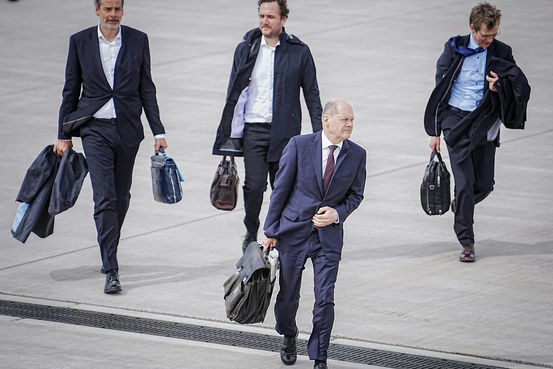 Bundeskanzler Olaf Scholz (vorne) geht im April 2023 auf dem militärischen Teil des Flughafens BER zum Regierungsflieger. Mit dabei: u.a. Steffen Hebestreit (l.).