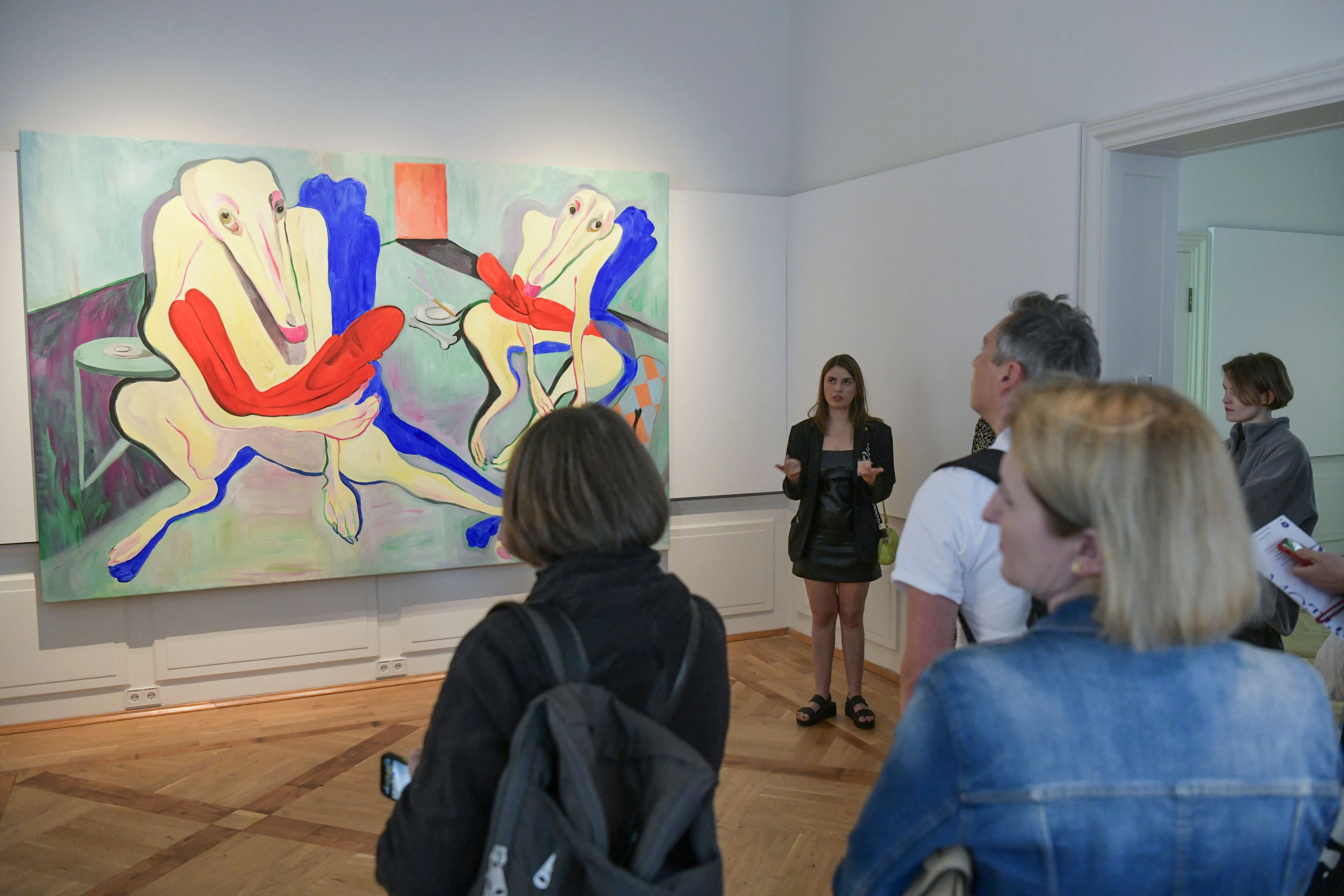 Valeria Schiller leitet durch die Ausstellung „Motherland: Ukrainische Künstler:innen hinterfragen Heimat“. Hinter ihr hängt das surrealistische Werk „Pietà“ von Alina Sokolova.