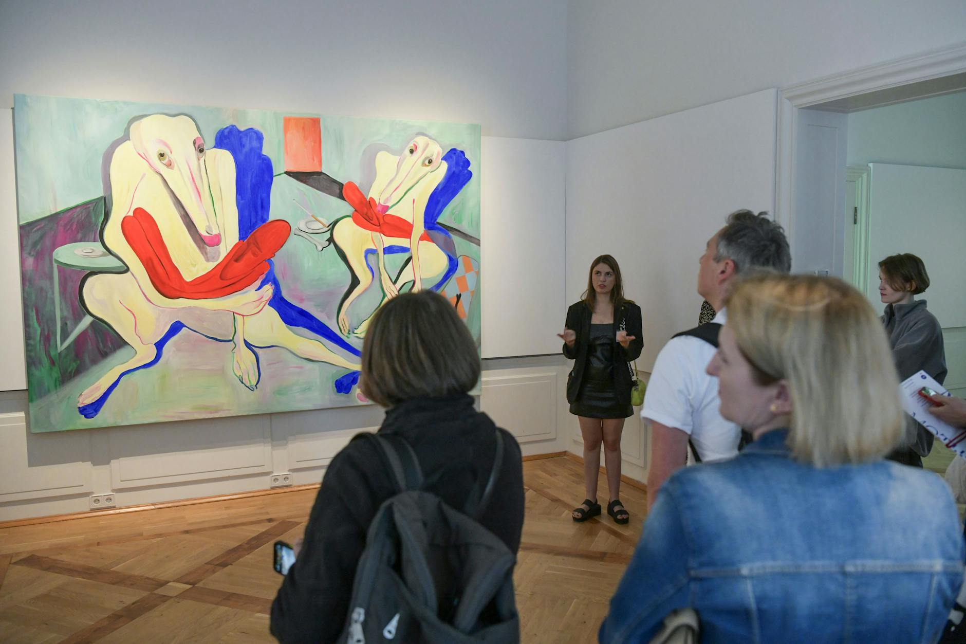 Valeria Schiller leitet durch die Ausstellung „Motherland: Ukrainische Künstler:innen hinterfragen Heimat“. Hinter ihr hängt das surrealistische Werk „Pietà“ von Alina Sokolova.