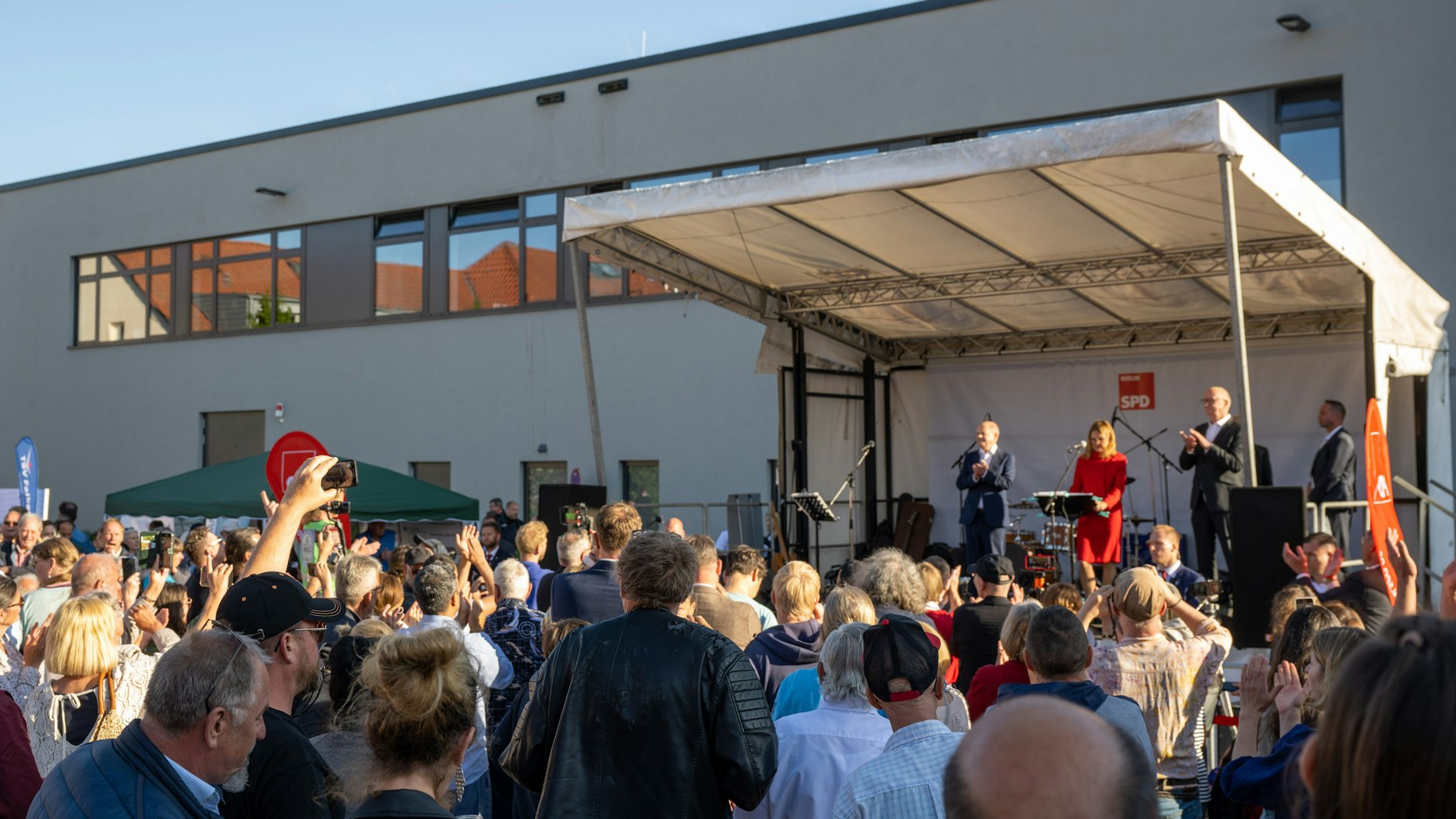 Besucher vom Europafest vor der Stadthalle, darunter auch Störer, stehen vor der Bühne, auf der Bundeskanzler Olaf Scholz spricht.