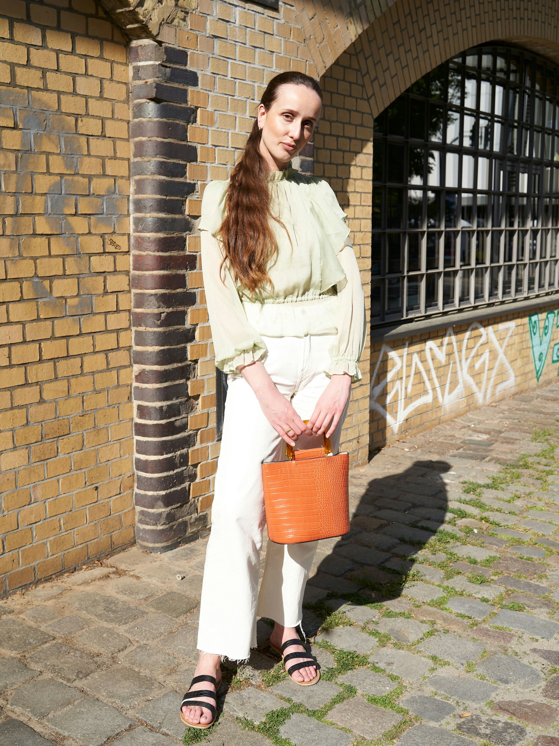 Unter all den Streetwear-Looks, die uns am Savignyplatz überrascht haben, begegnet sie uns dann doch noch: die typische Charlottenburger Eleganz. Hier in Gestalt der Modemanagement-Studentin Regina. Sie trägt ein romantisch gerafftes Oberteil von Mango, eine helle H&amp;M-Jeans sowie Sandalen von Asos. Ihre Tasche ist ebenfalls von Mango.