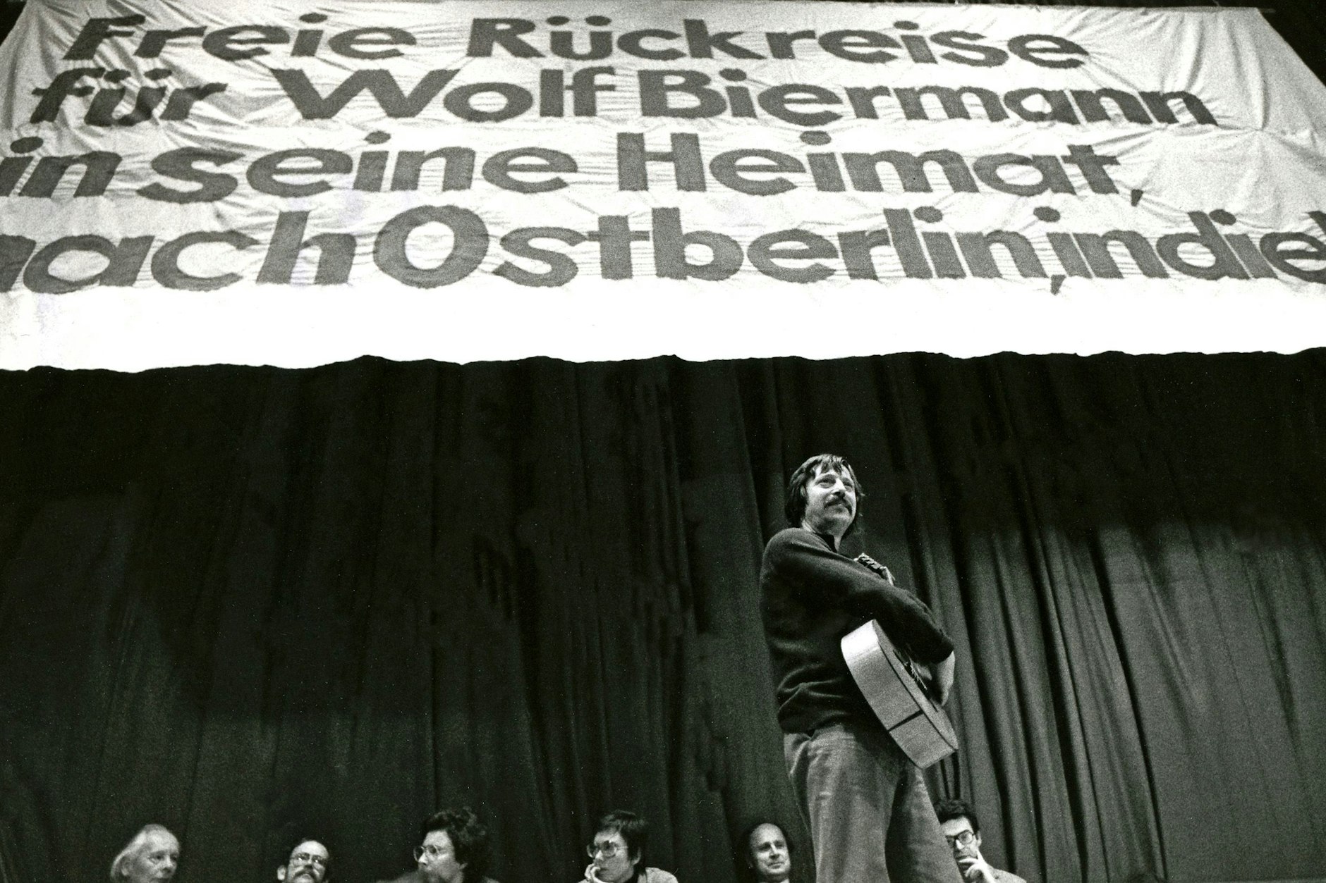 Solidaritätsveranstaltung mit Biermann am 19. November 1976 in Bochum. Auf dem Transparent steht die Forderung: „Freie Rückreise für Wolf Biermann in seine Heimat nach Ostberlin, in die DDR“.&nbsp;