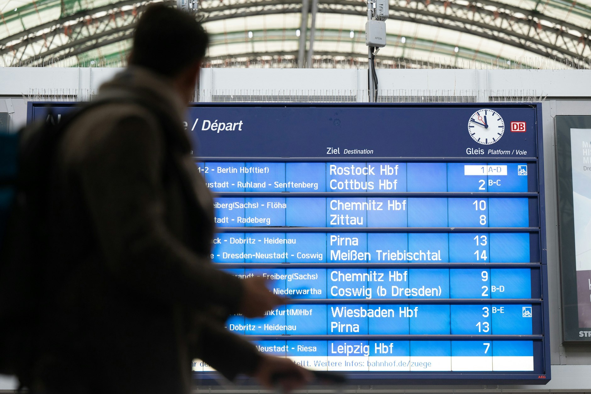Ein Fahrgast steht vor einer Anzeigetafel am Bahnhof.