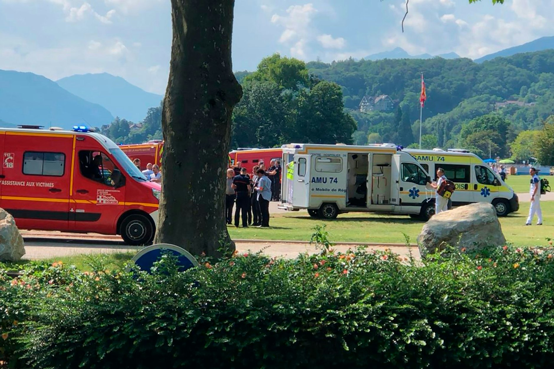 Krankenwagen und Rettungsfahrzeuge stehen am Einsatzort nach einem Messerangriff in einem Park.