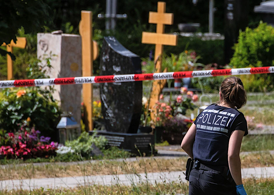 Altbach: Eine Polizistin geht über den abgesperrten Teil an einem Tatort auf einem Friedhof. Durch den Wurf eines explodierenden Gegenstands auf eine Trauergemeinde gab es mehrere Verletzte.