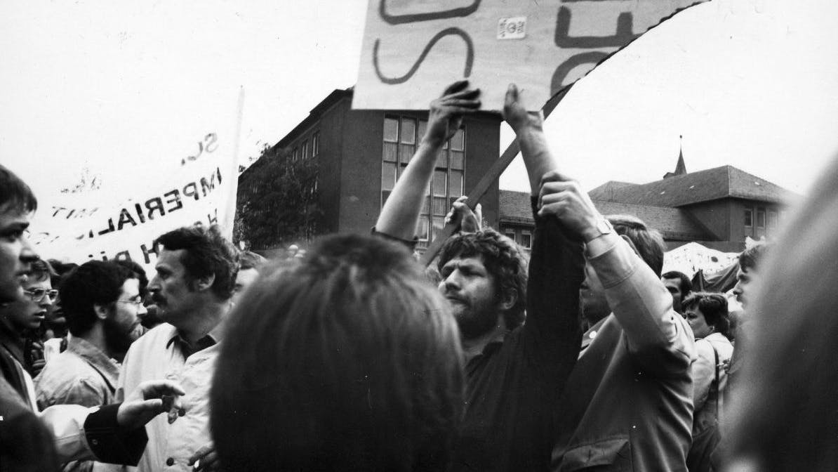 Roland Jahn wird auf einer Demonstration von Stasi-Leuten sein Transparent entrissen und zerstört, auf dem „Schwerter zu Pflugscharen“ steht - der Leitspruch der oppositionellen DDR-Friedensbewegung. 