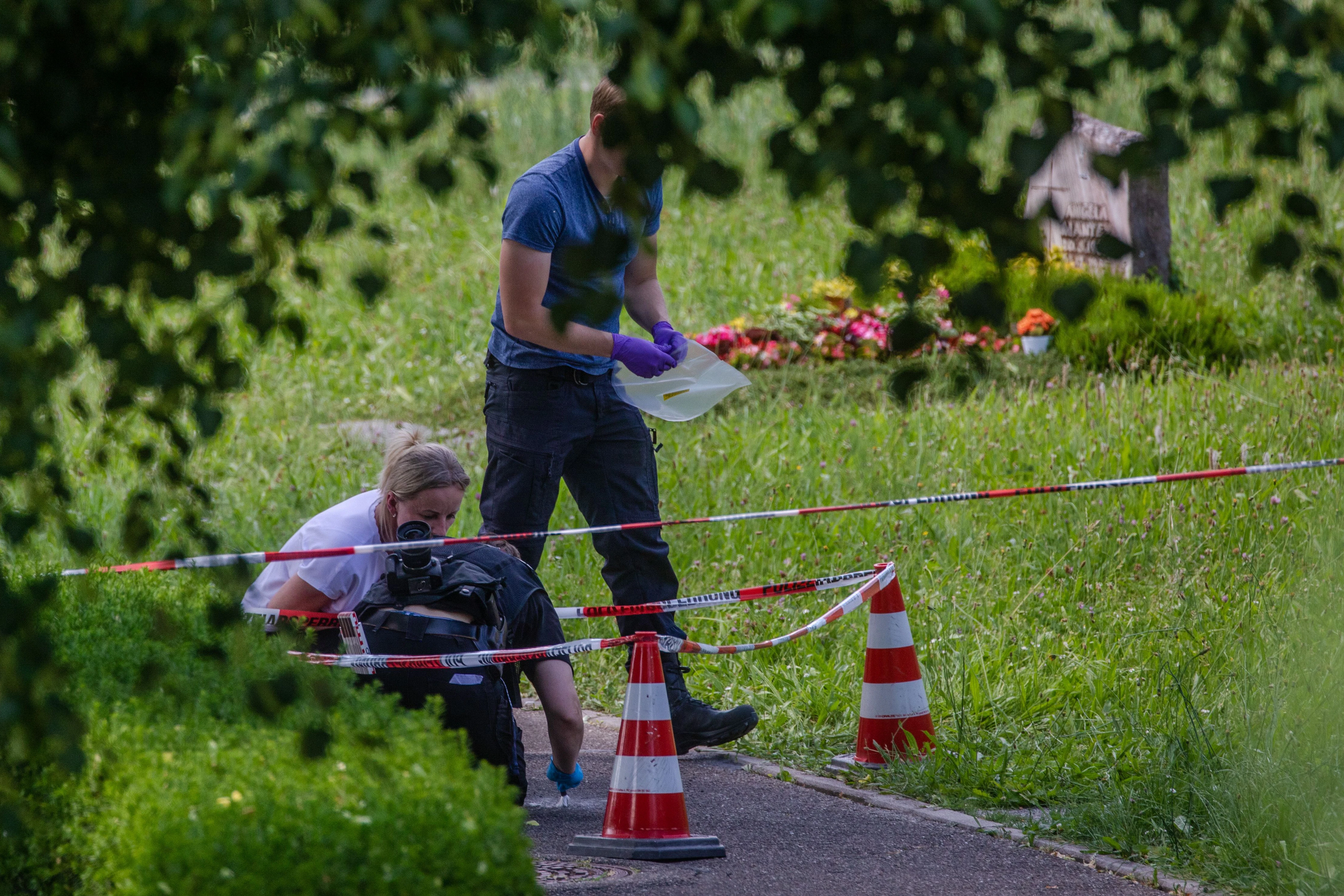 Altbach: Mitarbeiter der Spurensicherung suchen nach Spuren an einem Tatort auf einem Friedhof. Durch den Wurf eines explodierenden Gegenstands auf eine Trauergemeinde gab es mehrere Verletzte.