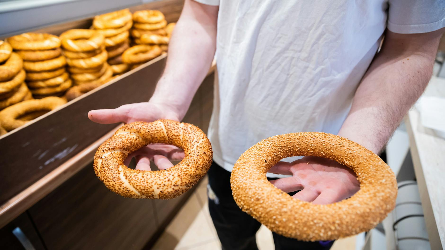 Cuma Cevik, Geselle und Sohn des Bäckereiinhabers Mehmet Cevik, zeigt zwei Simit, links die mit Traubensirup gesüßte Variante, die etwas dunkler ist.