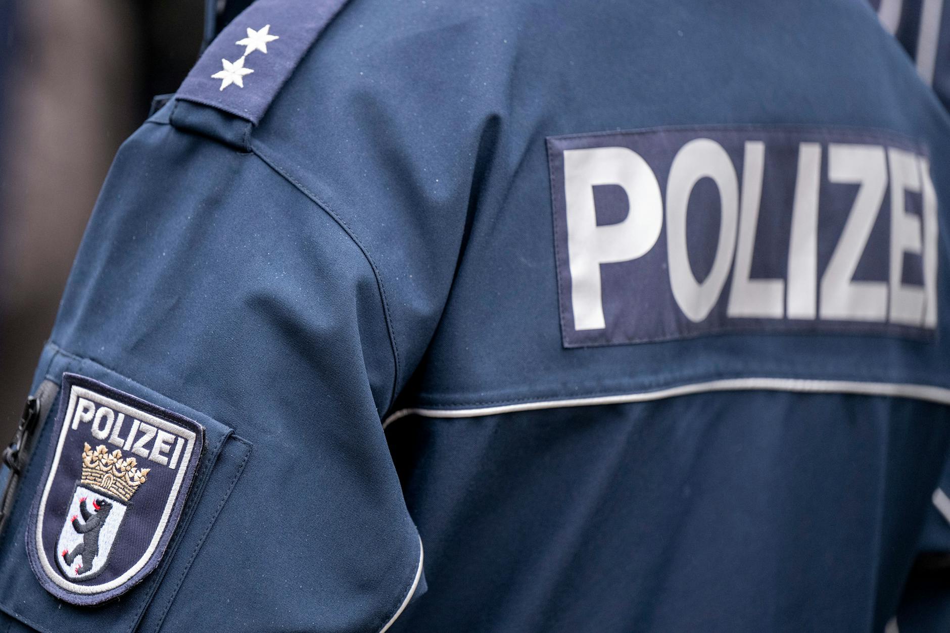 Die Aufschrift Polizei und das Wappen von Berlin auf der Uniform eines Polizeibeamten. 