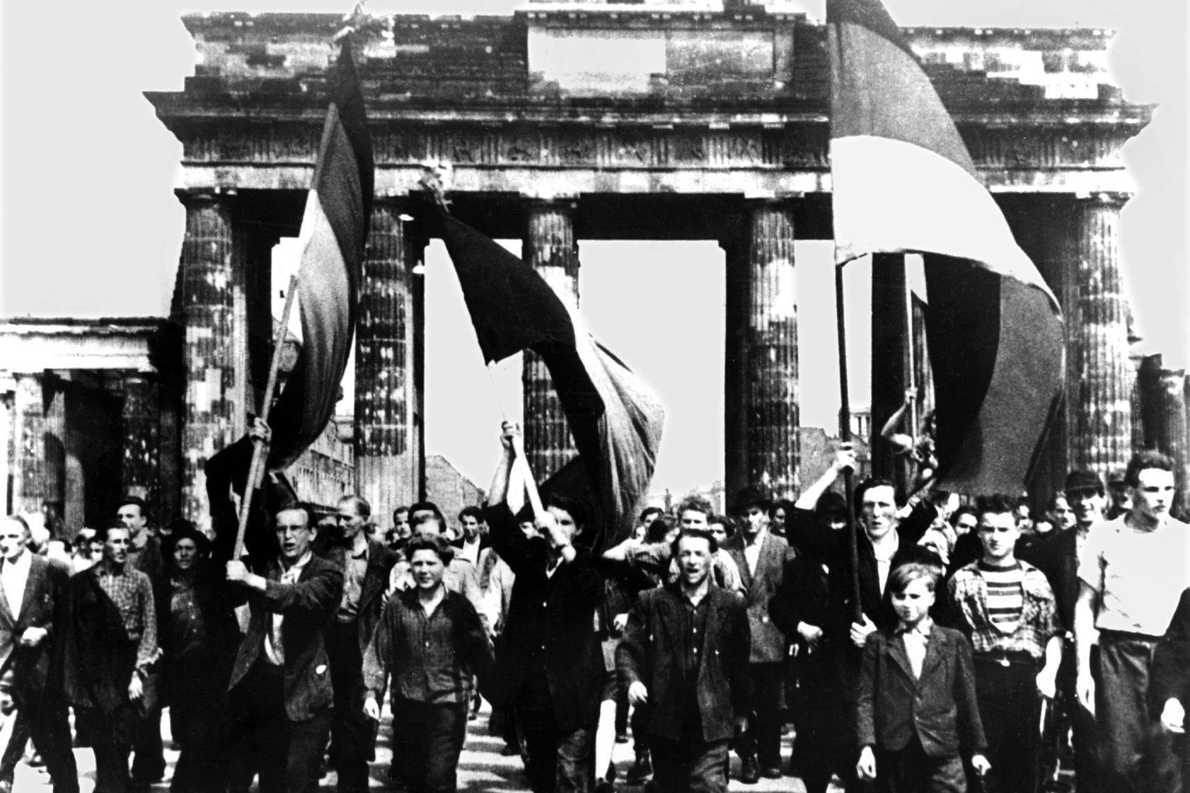 Ost-Berliner marschieren mit wehenden Fahnen vom Ost-Sektor aus durch das Brandenburger Tor. Am 17. Juni 1953 protestierten in der DDR eine Million Menschen gegen den noch jungen sozialistischen Staat – bis sowjetische Panzer den Aufstand beendeten. Dramatische Tage.