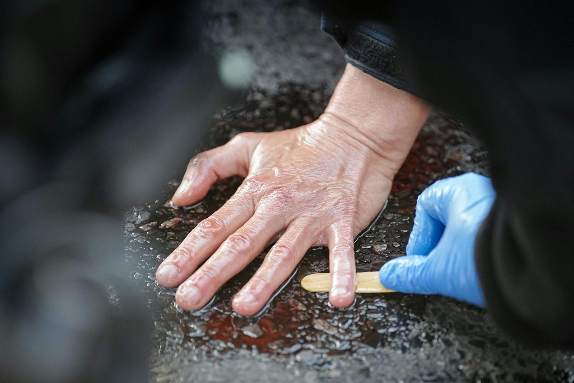 Berliner Polizei beim Versuch, Straße und Haut voneinander zu lösen bei einer Blockade der Letzten Generation.