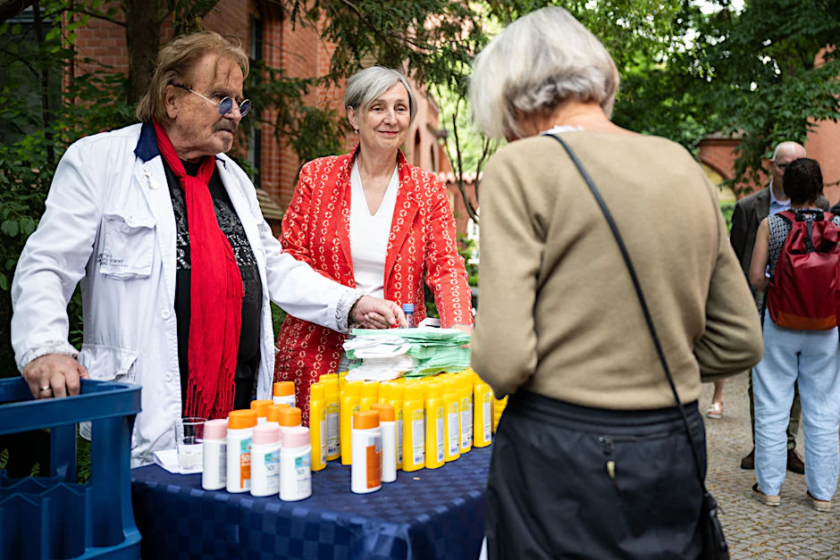 Frank Zander und Diakonie-Direktorin Ursula Shoen teilen Sonnencreme, Deo und Wasser aus.