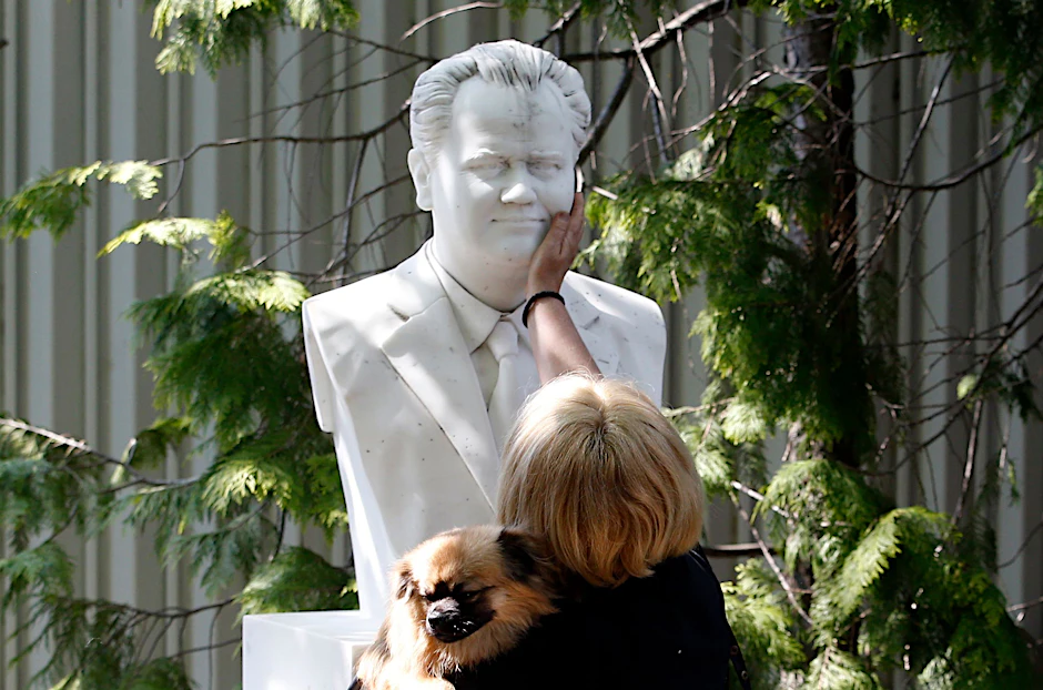 20. April 2019, Serbien, Pozarevac: Eine Frau berührt die Büste des früheren serbischen Präsidenten Slobodan Milošević während der Beerdigung seiner Witwe Mirjana Marković.