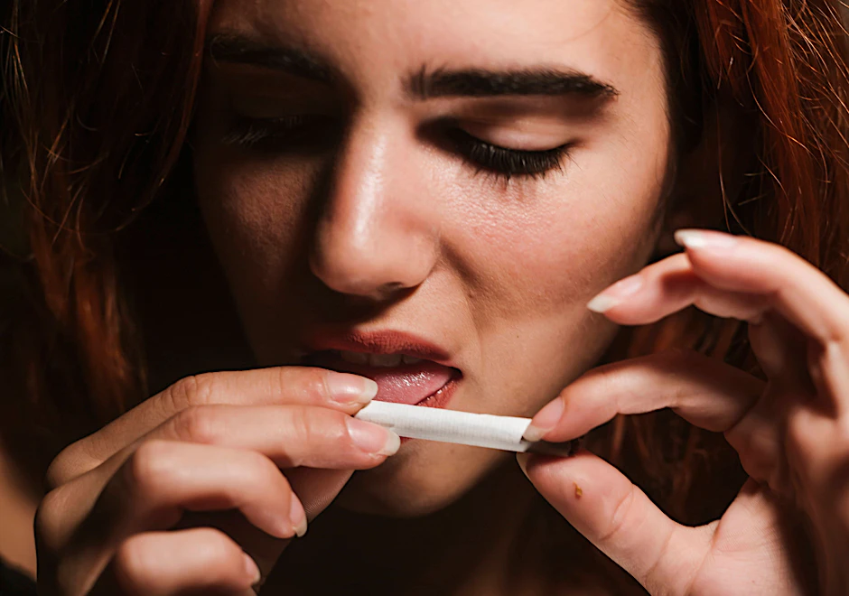 Eine Frau rollt einen Joint und befeuchtet das Zigarettenpapier.