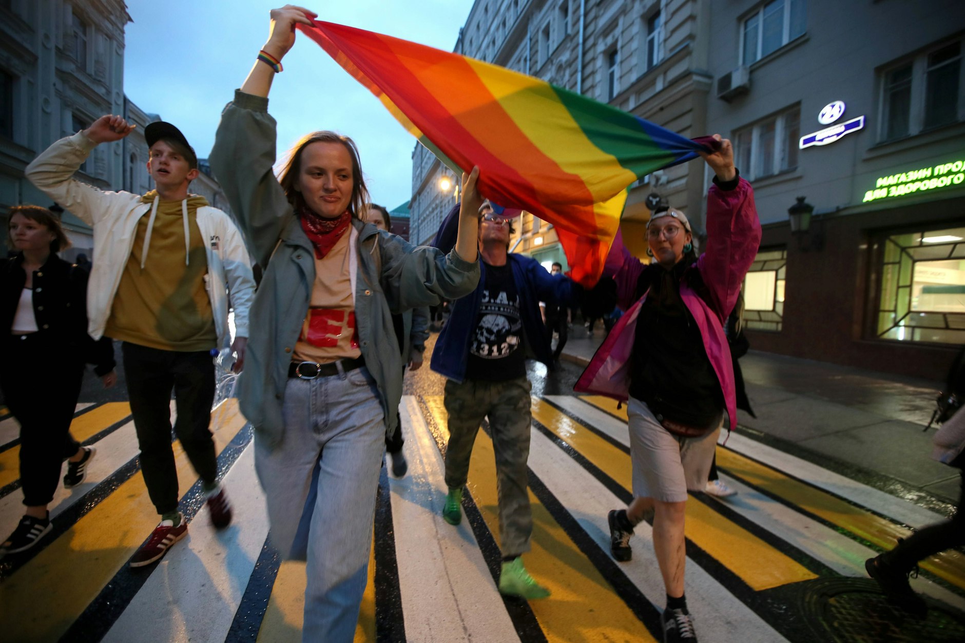 Junge Menschen laufen mit einer Regebogenfahne durch die Straßen von Moskau.