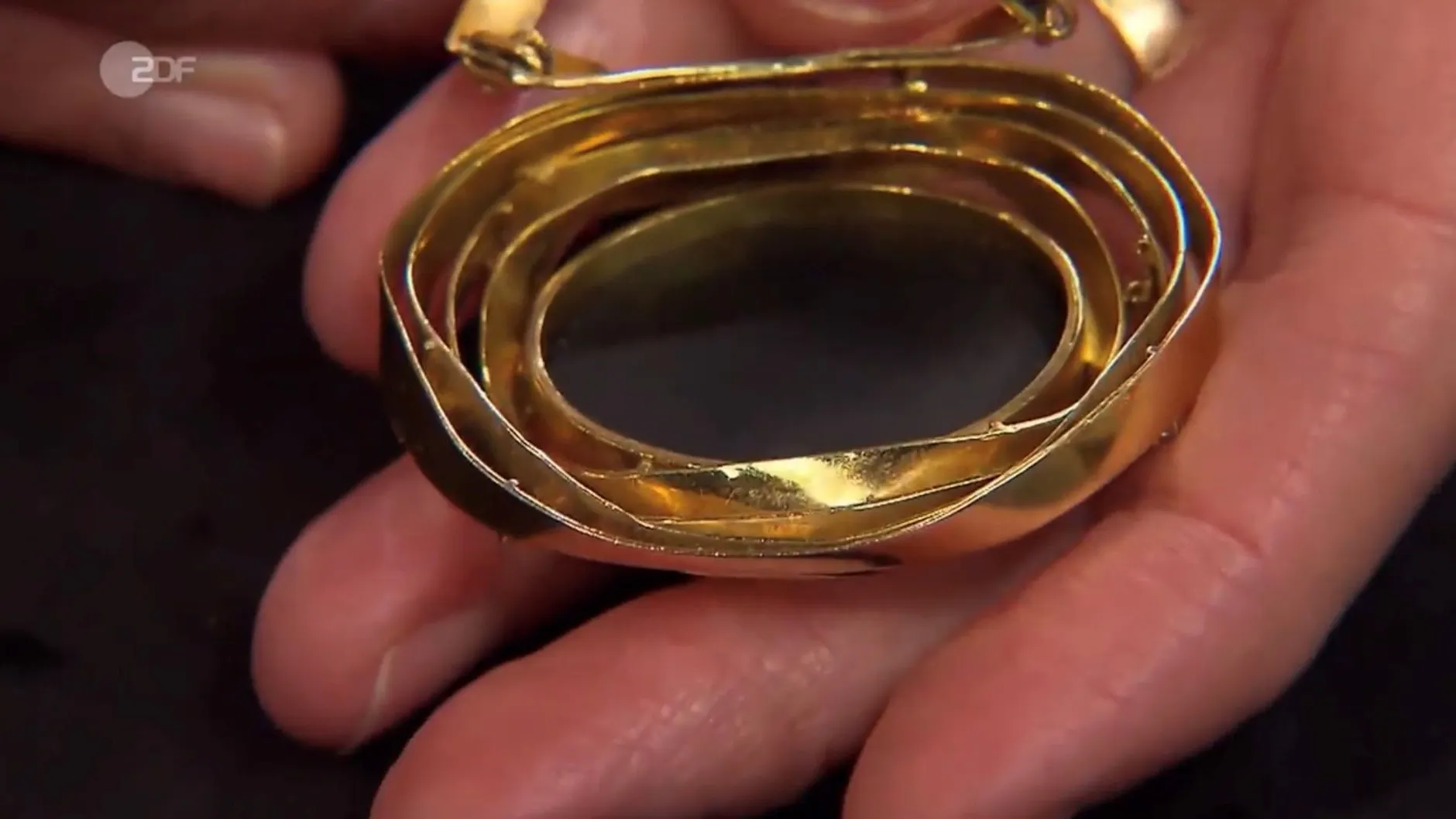 Die „Bares für Rares“-Expertin zeigt die Rückseite, bei der man erkennt, dass der Stein kein Vollschliff-Opal ist.