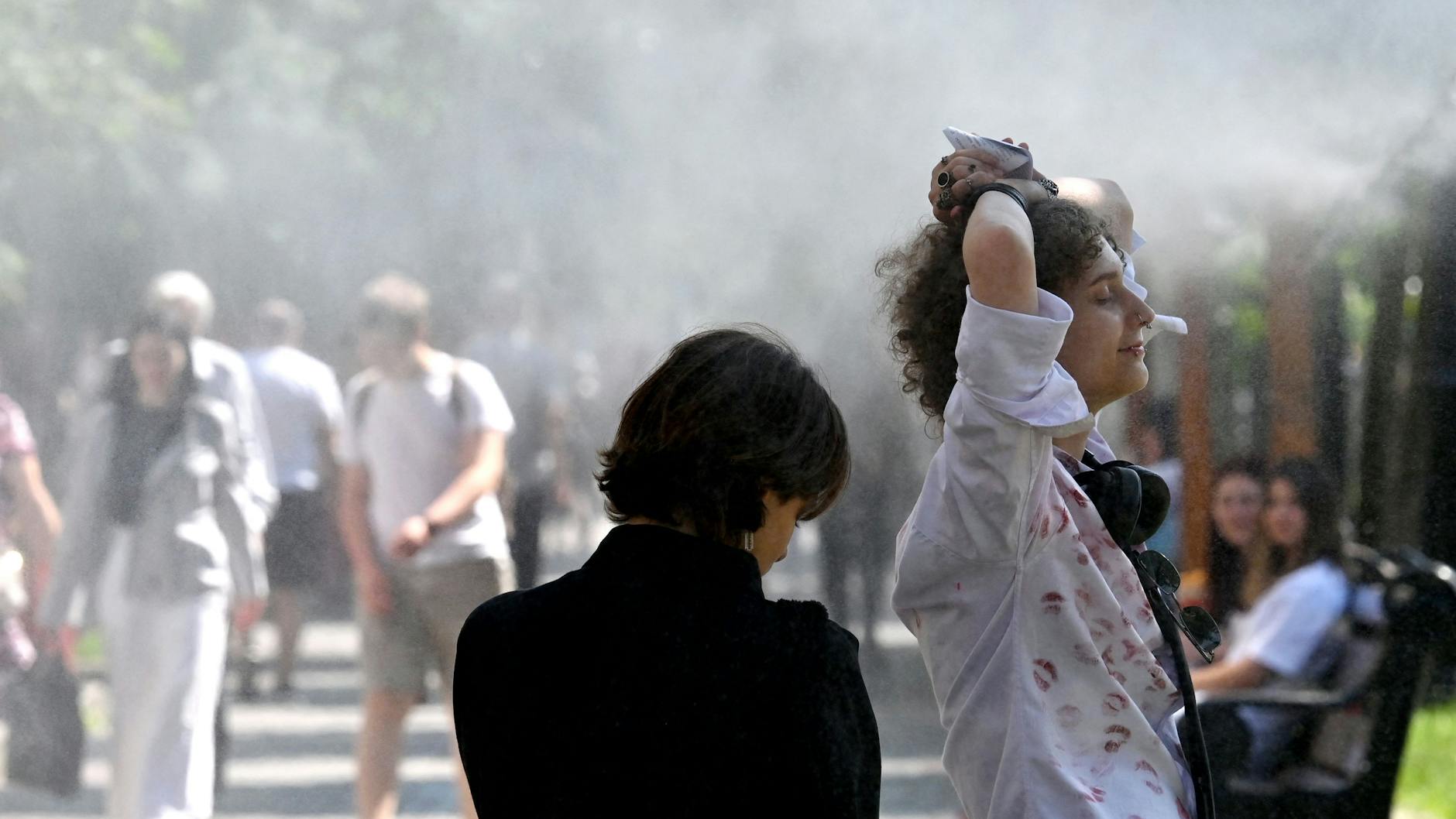 Stunden ohne Beschuss genießen: Eine Frau erfrischt sich in einer Kiewer Grünanlage an einem Wassersprinkler.