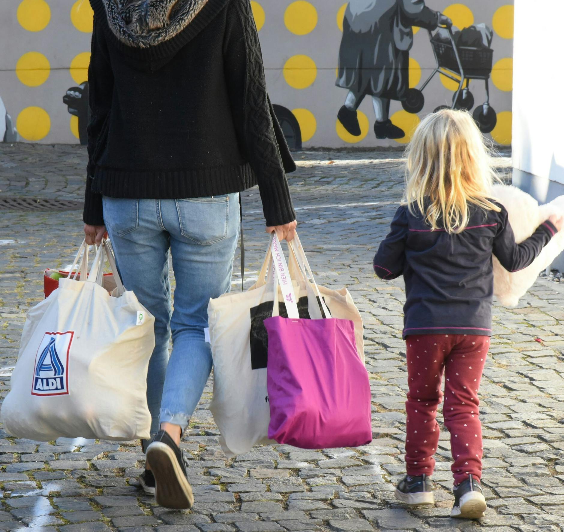 ARCHIV - An einer Ausgabestelle einer Tafel gehen eine Frau und ein Kind mit gespendeten Lebensmittel nach Hause.