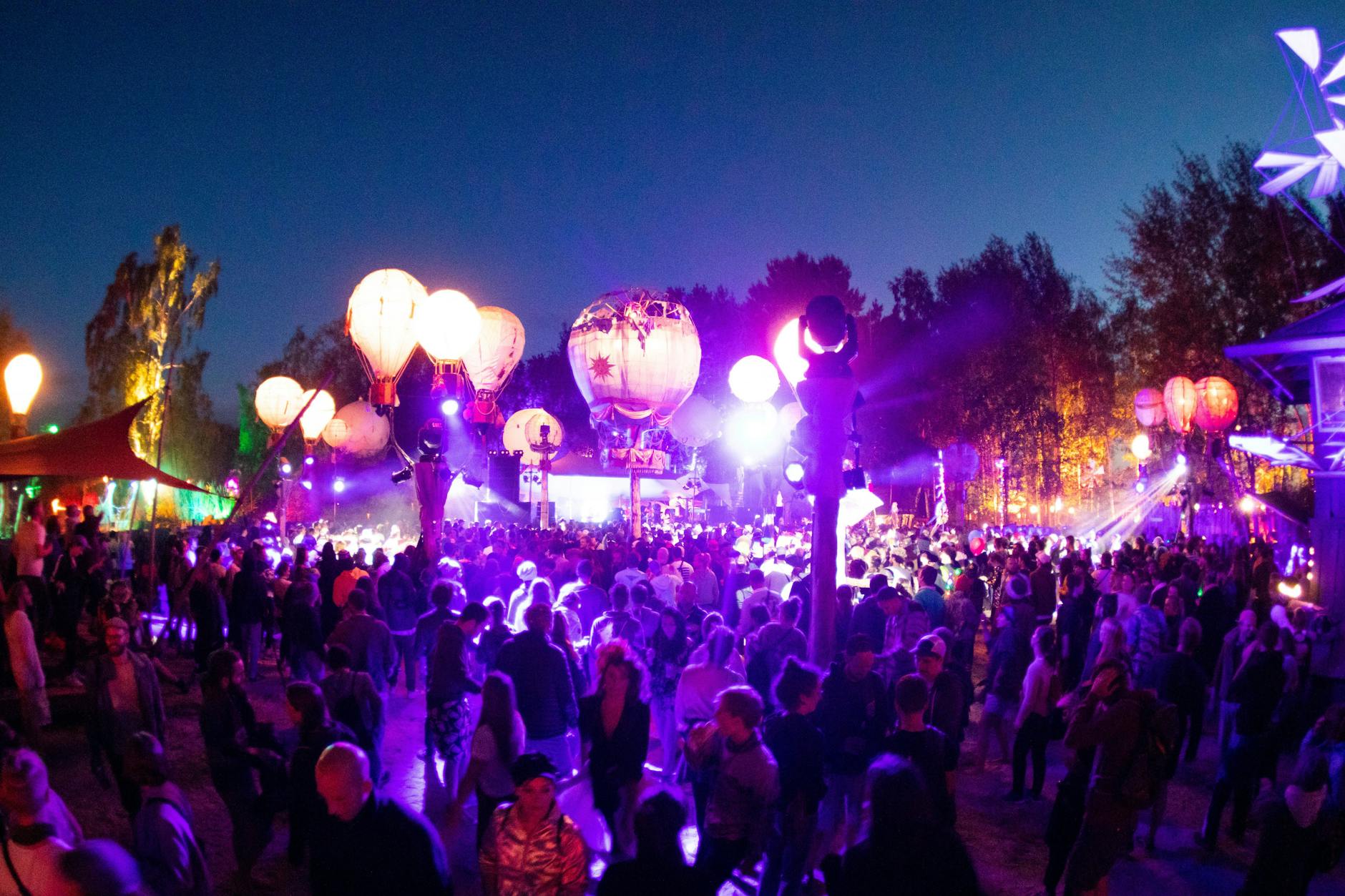 Besucher tanzen auf einer mit leuchtenden Ballonen geschmückten Bühne auf dem Gelände des Fusion-Festivals.
