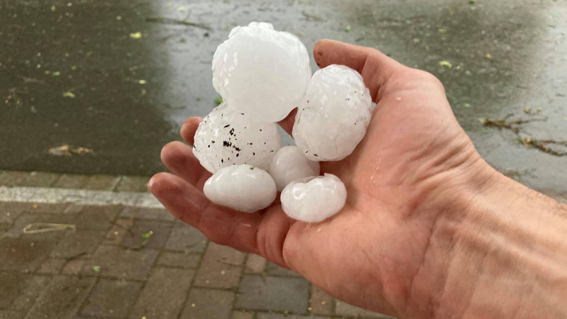Ein Mann hält Hagelkörner, die am Donnerstagabend im oberbayrischen Valley bei einem Gewitter niedergegangen sind.