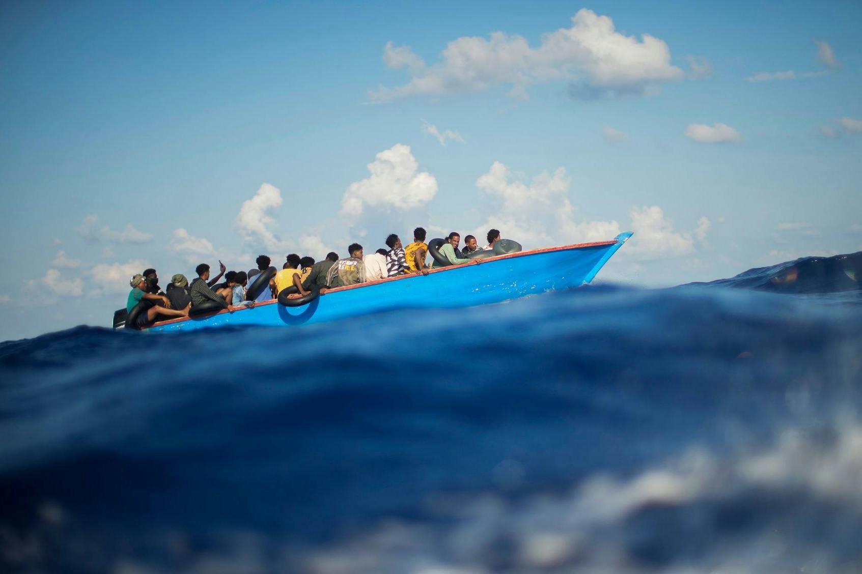 Migranten sitzen in einem Holzboot südlich der italienischen Insel Lampedusa auf dem Mittelmeer. 