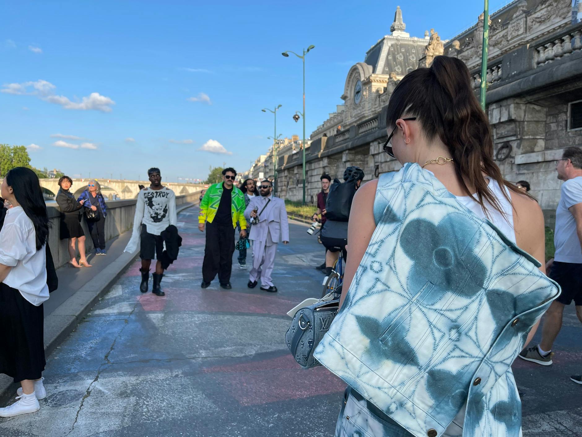 Eine Dame hat sich ihre Louis-Vuitton-Jeansjacke kunstvoll um den Oberkörper drapiert.