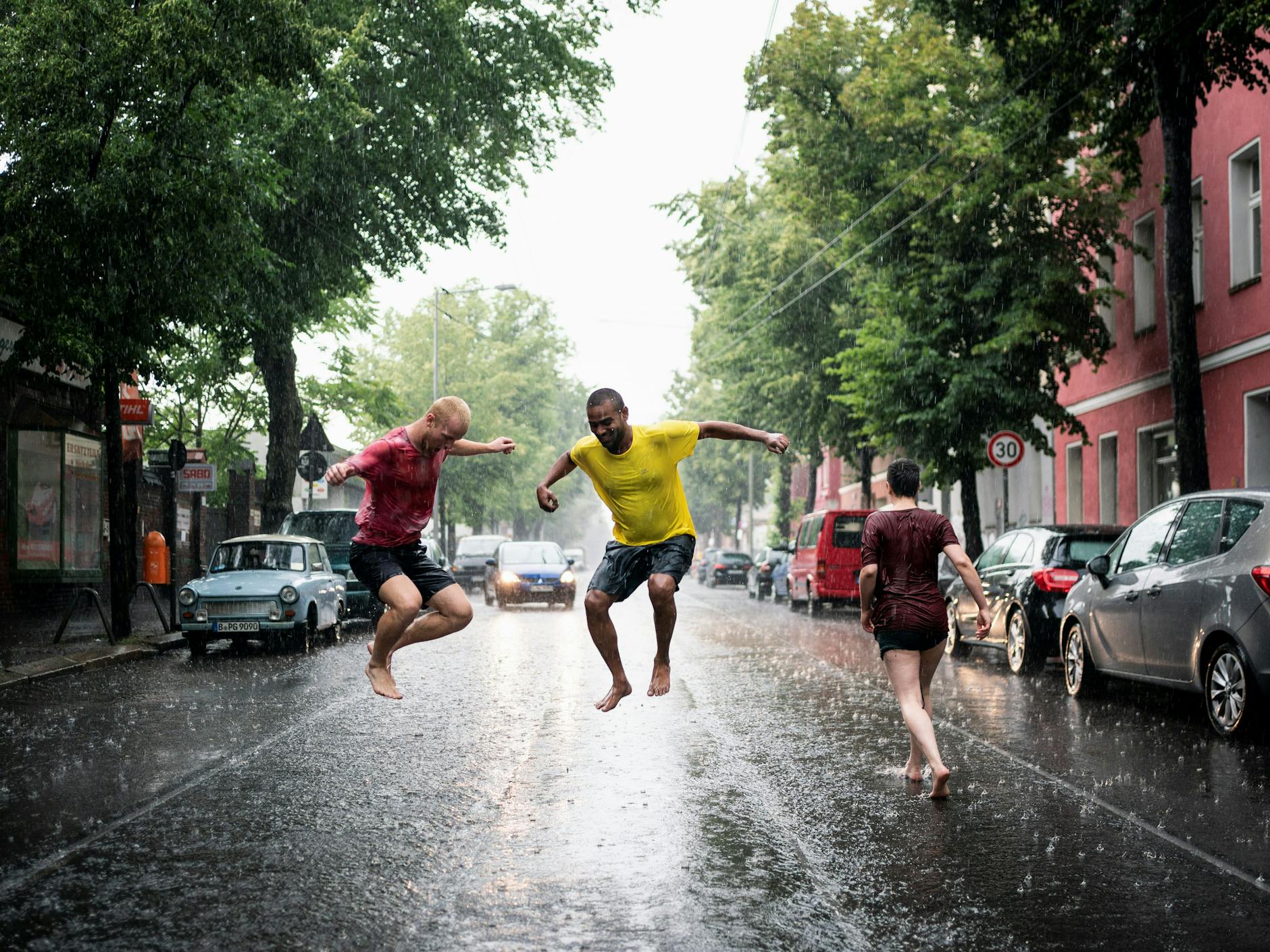 Junge Menschen laufen während eines Gewitters durch die nassen Straßen von Berlin.