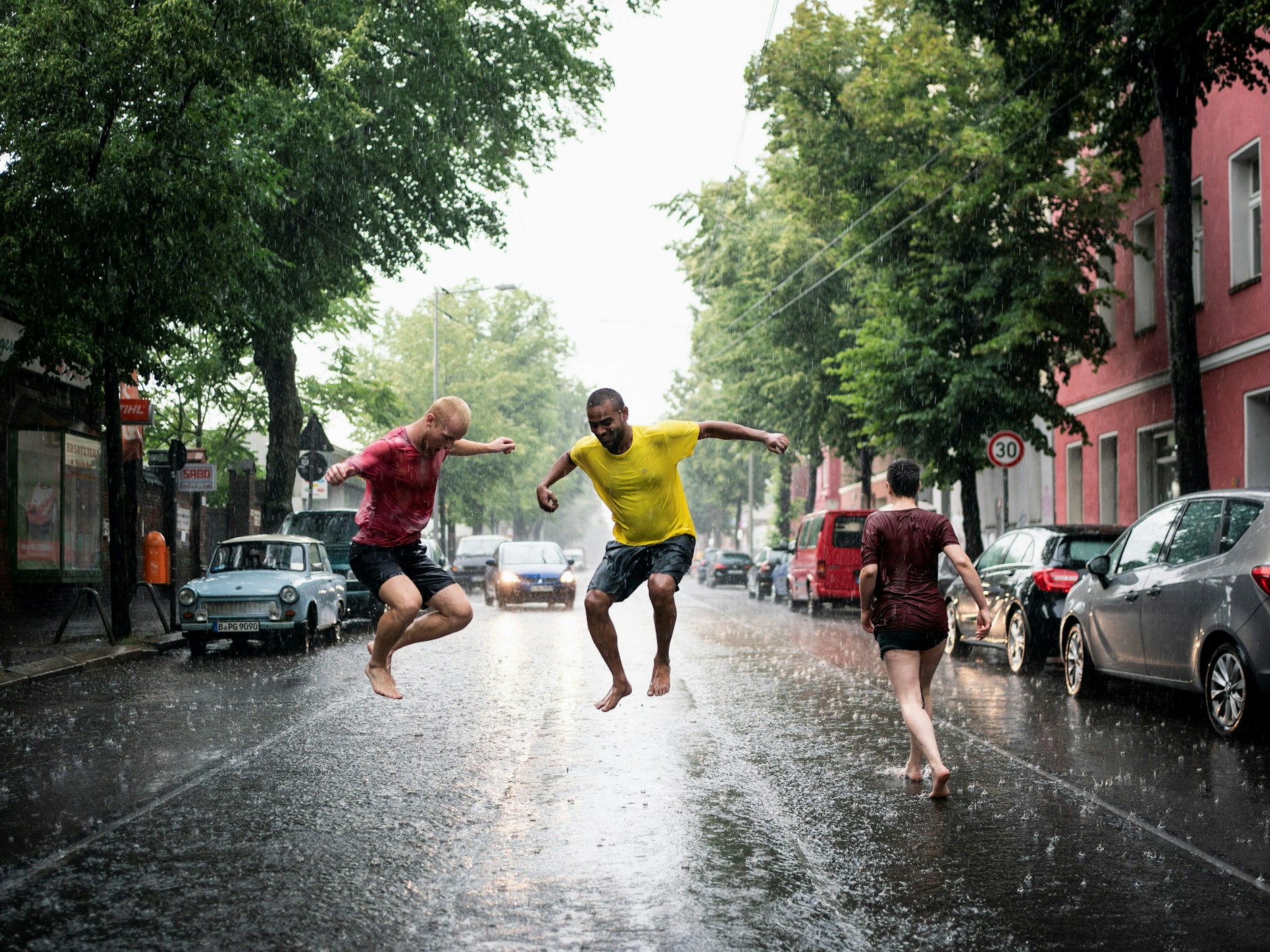 Junge Menschen laufen während eines Gewitters durch die nassen Straßen von Berlin.