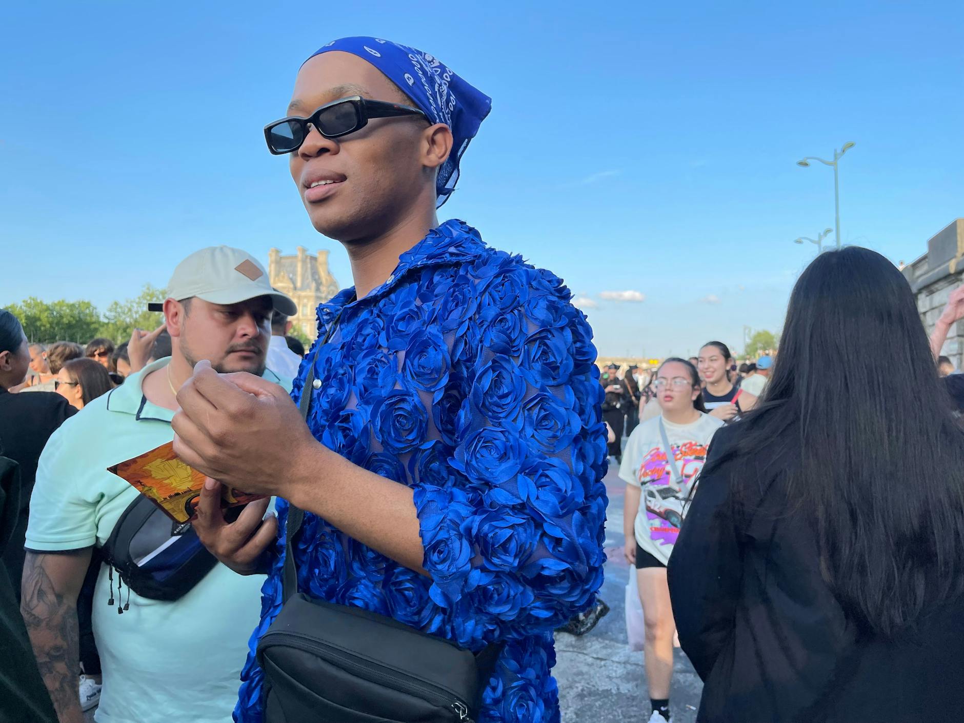 Blaue Rosen an diesem Gast; in der Hand hält er die Einladung für die Louis-Vuitton-Show.