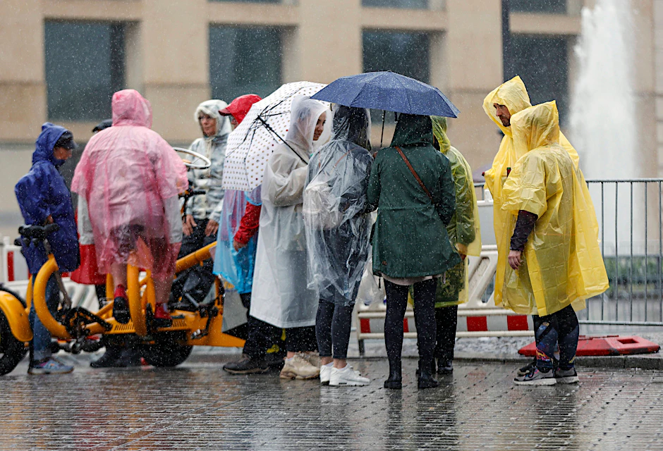 Touristen schützen sich in Berlin vor heftigem Regen.