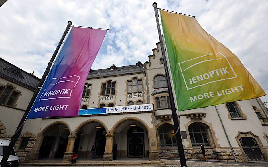 Banner mit dem Logo der Jenoptik AG wehen während der Hauptversammlung des Unternehmens vor dem Volkshaus in Jena.  