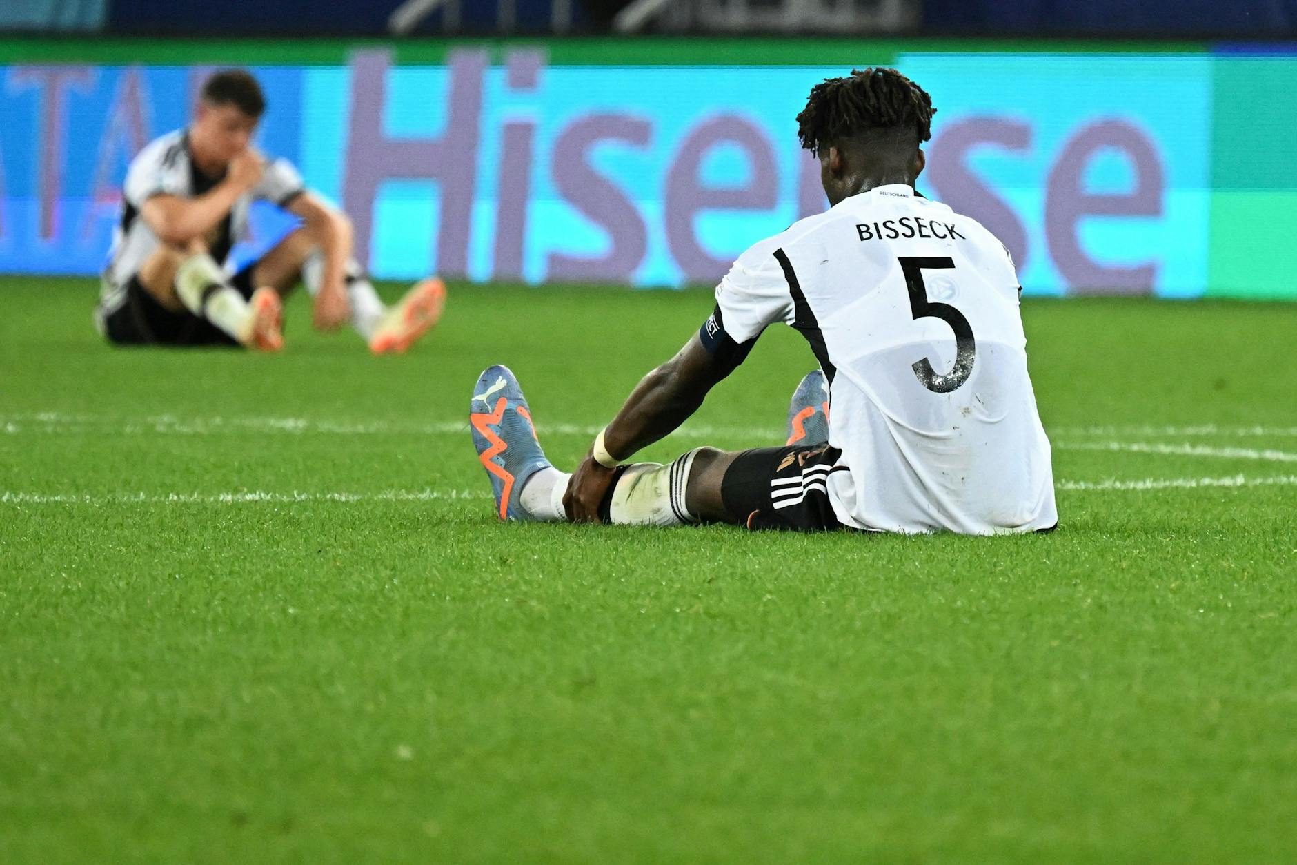 Deutschlands Yann Bisseck (vorn) sitzt nach dem Abpfiff enttäuscht auf dem Rasen.
