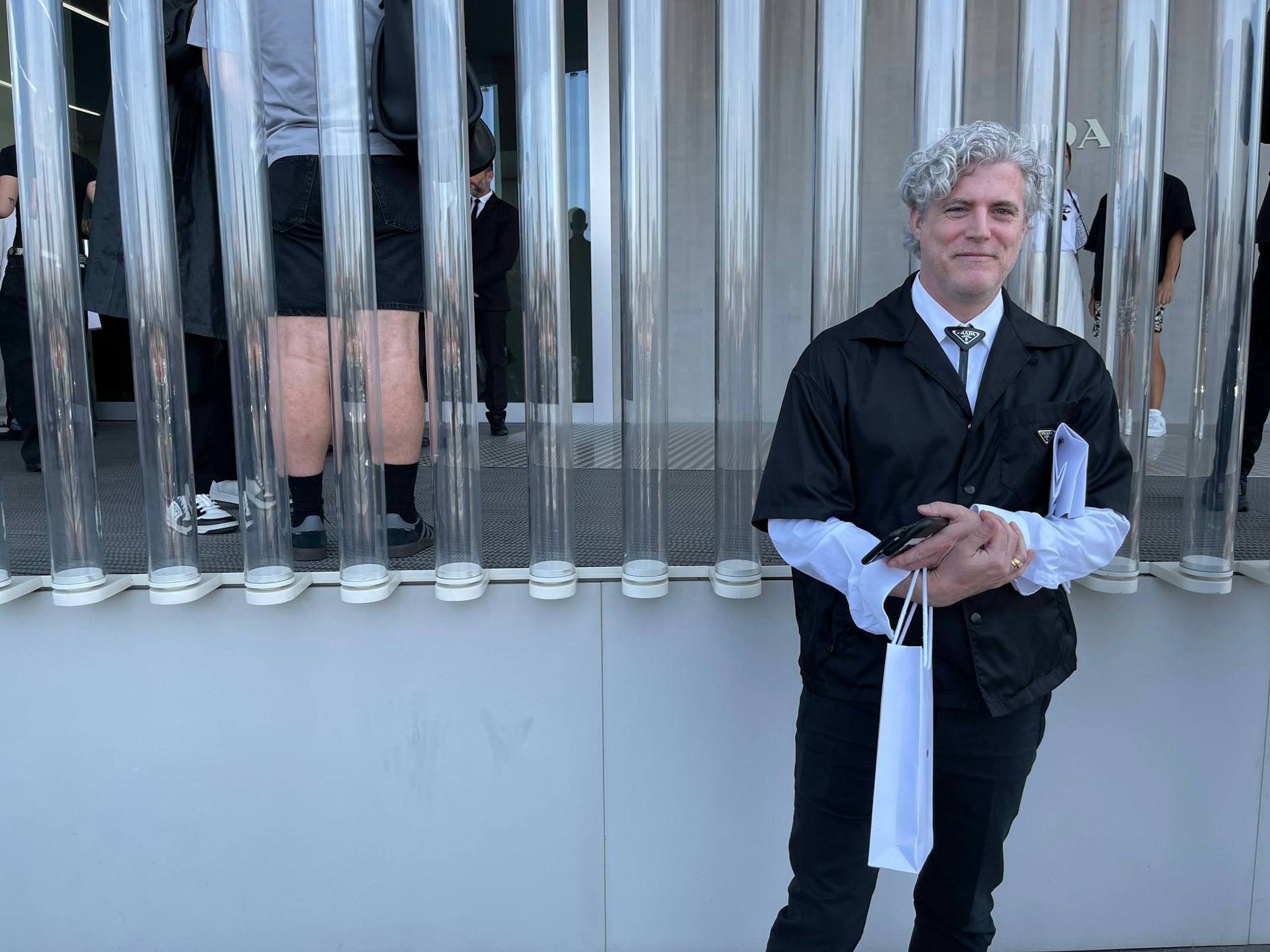 Ein fesch gekleideter Prada-Mitarbeiter mit schönen Locken wartet auf seine Gäste.&nbsp;