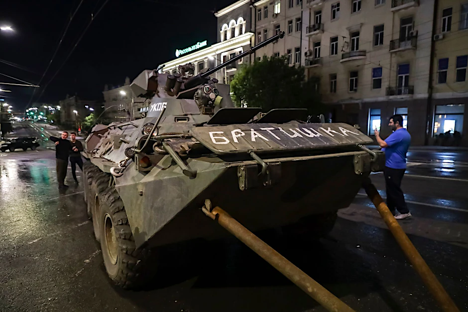Menschen gehen um ein gepanzertes Fahrzeug des Militärunternehmens Wagner Group mit der Aufschrift «Brother» herum, bevor sie ein Gelände am Hauptsitz des Südlichen Militärbezirks auf einer Straße in Rostow am Don verlassen.  