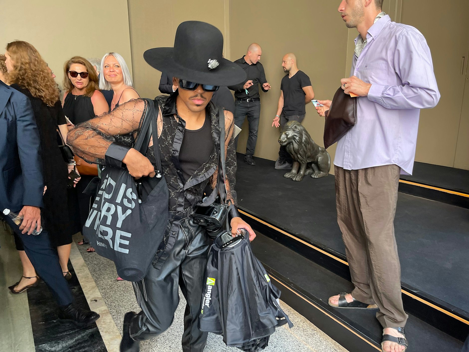 Ein exzentrisch gekleideter Fotograf betritt den Hof.