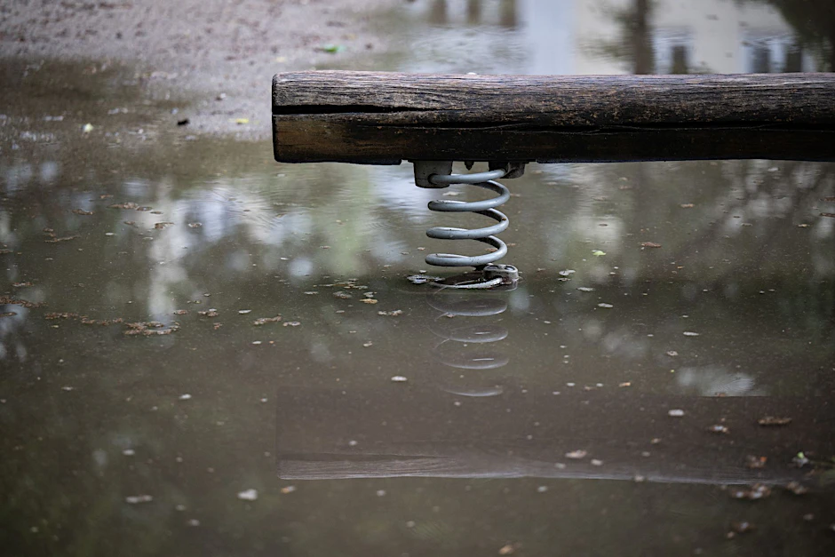 Eine Wippe auf einem Spielplatz steht im Wasser.  