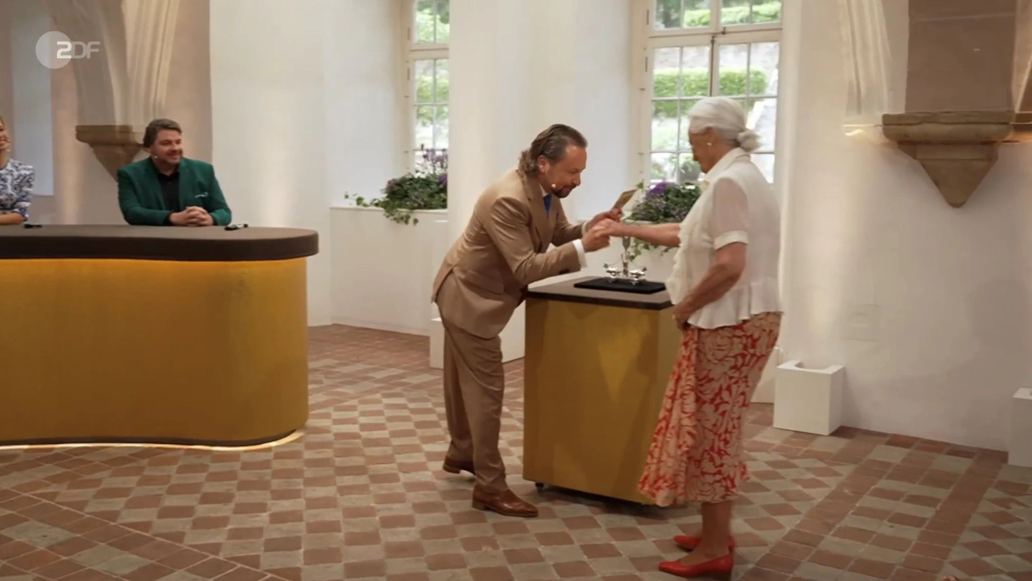 „Bares für Rares“-Händler Wolfgang Pauritsch küsst ganz Gentleman die Hand der Verkäuferin, als er bei 2400 Euro den Zuschlag bekommt.