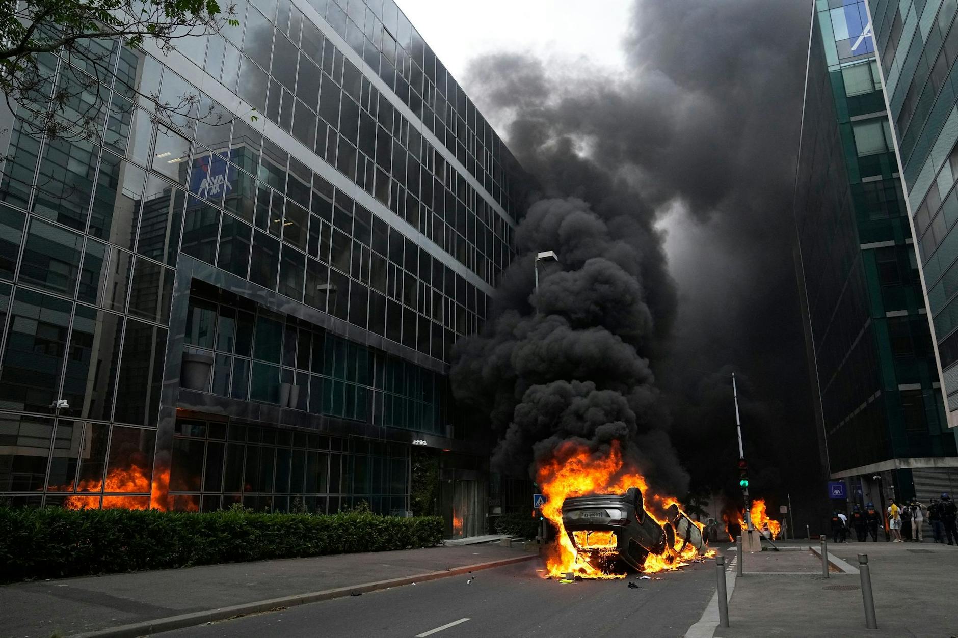 Brennende Autos liegen nach einem Trauermarsch in Nanterre auf einer Straße.